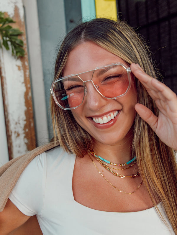 happy woman wearing necklace and touching red glasses