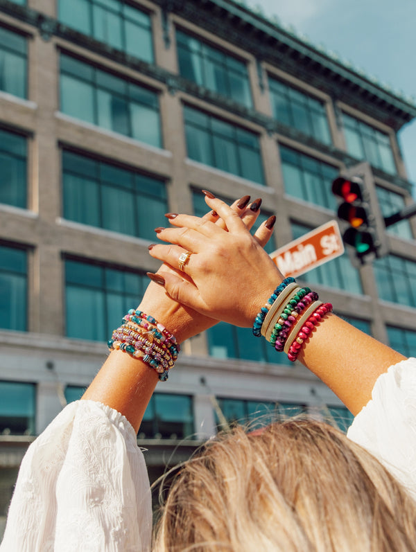 woman with arms crossed showcasing multiple bracelet stacks